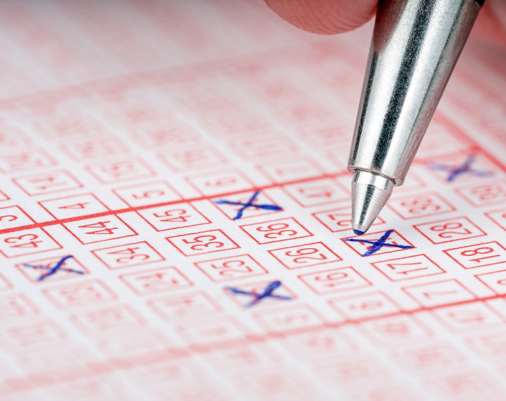 Close-up of a pen marking numbers on a lottery ticket.